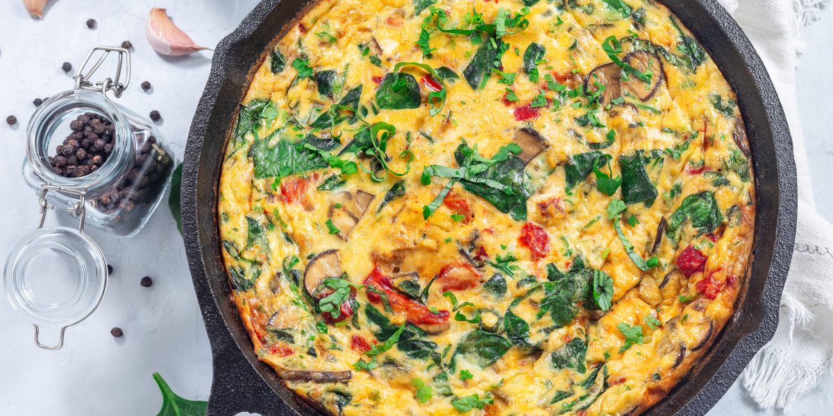 Brunch egg frittata with spinach, roasted red peppers, mushrooms, in cast iron, horizontal, top view